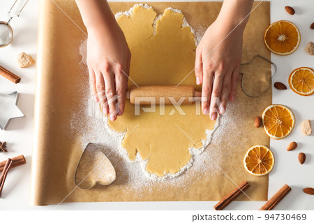 Woman cooking cookies, using cookie cutter and rolling pin 94730469