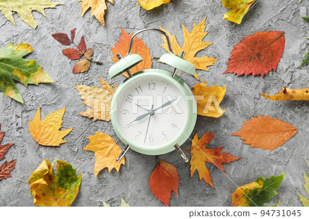 Autumn leaves and alarm clock on gray textured background 94731045