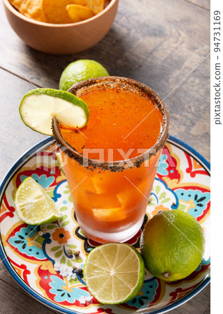 Homemade michelada cocktail with beer, lime juice,hot sauce,salted rim and tomato juice on wooden table Homemade michelada cocktail with beer, lime juice,hot sauce,salted rim and tomato juice on wooden table 94731169