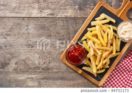 Fried potatoes with ketchup and Mayonnaise on wooden table 94731173