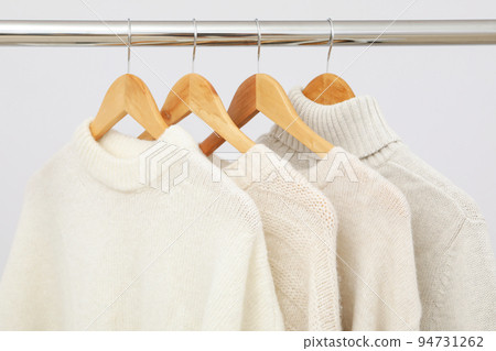 Wardrobe rack with hangers with sweaters on light background Wardrobe rack with hangers with sweaters on light background 94731262