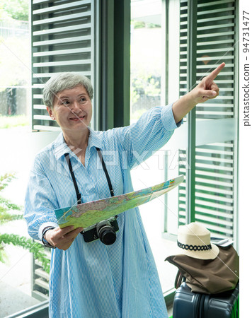 Portrait of mature aged asian woman 60s holding a map in concept of tourism to travel, Travel or exploring concept. Portrait of mature aged asian woman 60s holding a map in concept of tourism to travel, Travel or exploring concept. 94731477