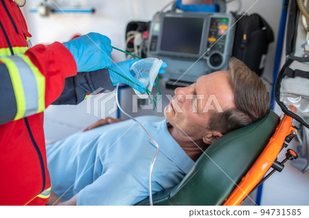 Paramedic preparing an unconscious man for oxygen therapy 94731585