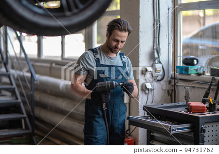 Focused car technician using the drill in his workshop 94731762