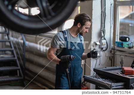 Automotive technician preparing for work in his workshop 94731764