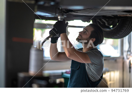 Concentrated automotive technician fixing the client vehicle Concentrated automotive technician fixing the client vehicle 94731769