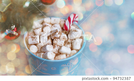 winter mug with marshmellow against background of festive lights bokeh and fir branches 94732387