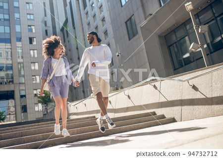 Young couple walking in the street and holding hands Young couple walking in the street and holding hands 94732712