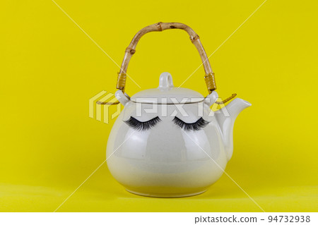 White teapot with eyes on a yellow background. White teapot with eyes on a yellow background. 94732938