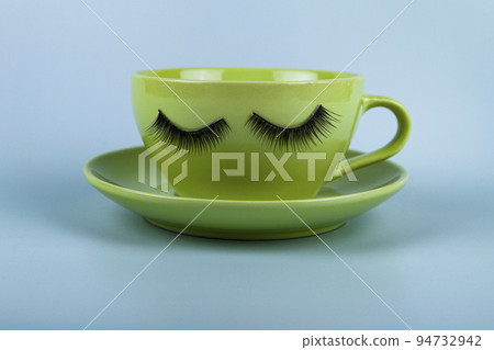 Funny green cup with eyes on a blue background. Funny green cup with eyes on a blue background. 94732942