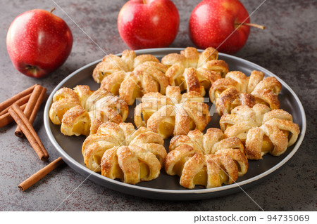 baked apples wrapped in puff pastry and sprinkled with sugar and cinnamon close-up in a plate. horizontal 94735069