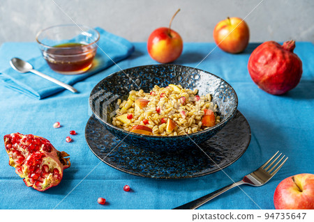 Sweet homemade barley porridge with pomegranate seeds, apples and honey. Rosh Hashanah celebration Sweet homemade barley porridge with pomegranate seeds, apples and honey. Rosh Hashanah celebration 94735647