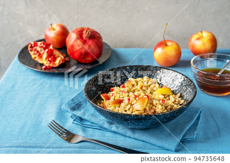 Sweet homemade barley porridge with pomegranate seeds, apples and honey. Rosh Hashanah celebration Sweet homemade barley porridge with pomegranate seeds, apples and honey. Rosh Hashanah celebration 94735648