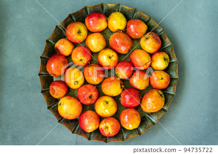 Ripe red small Ranetka apples on a metal plate, on a gray or blue background. Ripe red small Ranetka apples on a metal plate, on a gray or blue background. 94735722