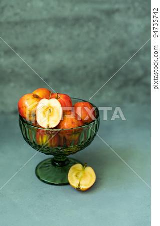 Fresh red apples in a glass vase on a gray background Fresh red apples in a glass vase on a gray background 94735742