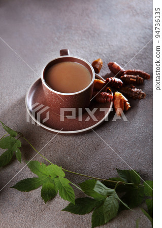 A cup of coffee and a pastille. The pastille is rolled into a roll. A branch with leaves. Healthy food without sugar.Vertical photo. A cup of coffee and a pastille. The pastille is rolled into a roll. A branch with leaves. Healthy food without sugar.Vertical photo. 94736135
