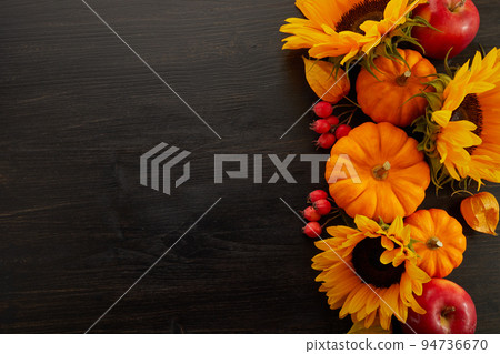 Pumpkin and sunflowers over old wooden background with copy space. Autumn background decoration. Pumpkin and sunflowers over old wooden background with copy space. Autumn background decoration. 94736670
