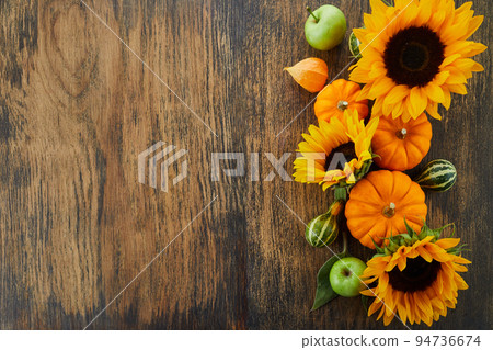 Pumpkin and sunflowers over old wooden background with copy space. Autumn background decoration. Pumpkin and sunflowers over old wooden background with copy space. Autumn background decoration. 94736674