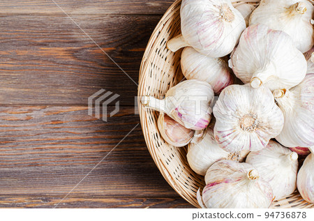 Garlic in a wicker basket. Brown wooden background. Copy space. 94736878