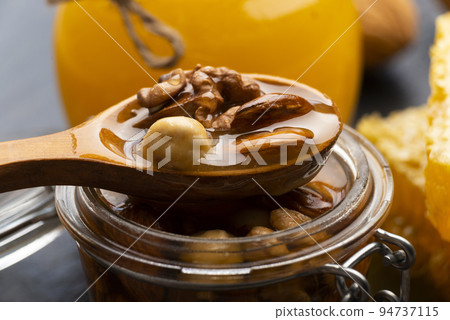 Honeyed assorted nuts in wooden spoon over mason jar organic food background 94737115