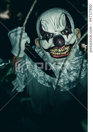 evil clown with a knife in the woods at night 94737900