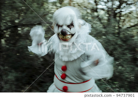 evil clown in motion in the woods at dusk evil clown in motion in the woods at dusk 94737901