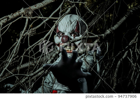 scary evil clown in the woods at night 94737906