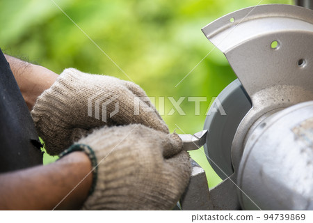 The worker regrinding the lathe tool with dressing wheel. 94739869