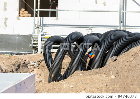 Black PVC flexible corrugated plastic insulation pipes tubing of electrical cables wire at undeground installation. New modern building construction site with engineering pipeline drainage technology 94740378