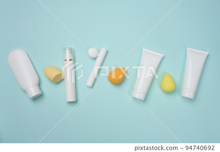 White plastic tubes for cream, gel and other cosmetics and sponges on a blue background White plastic tubes for cream, gel and other cosmetics and sponges on a blue background 94740692