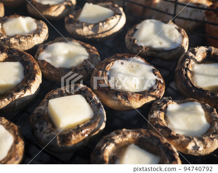 Cheese stuffed mushrooms. Grilled champignons filled with cheese. Hot portobello cups with melted mozzarella on the grill grate Cheese stuffed mushrooms. Grilled champignons filled with cheese. Hot portobello cups with melted mozzarella on the grill grate 94740792