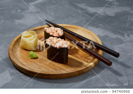 Warm rolls with tuna, salmon, perch, eel, tobiko caviar, nori, rice, cucumber on wooden board gray stone background. 94740998