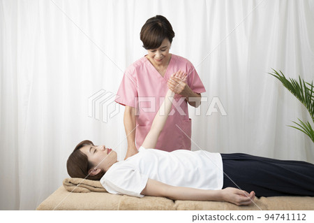 A woman who receives a manipulative treatment and a woman who is a manipulative therapist A woman who receives a manipulative treatment and a woman who is a manipulative therapist 94741112