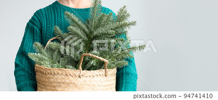 Women's in red pullover holding Christmas spruce Danish branches for make decoration. Women's in red pullover holding Christmas spruce Danish branches for make decoration. 94741410
