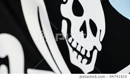 Black pirate flag with skull symbol on the desert island 94741928