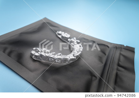 new transparent plastic braces lie on a special orthodontic package with a zipper on a blue background, studio shot, nobody 94742086