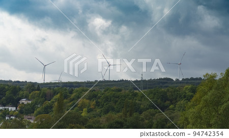 Wind turbines generate electricity on wooded hills Wind turbines generate electricity on wooded hills 94742354