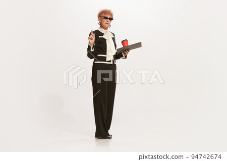 Portrait of beautiful senior woman in retro vintage style outfit posing isolated on white background. Concept of beauty, old generation, fashion, emotions 94742674