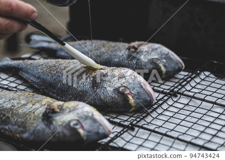cooking sea fish. Raw dorado fish with spices on bbq mesh. cooking sea fish. Raw dorado fish with spices on bbq mesh. 94743424