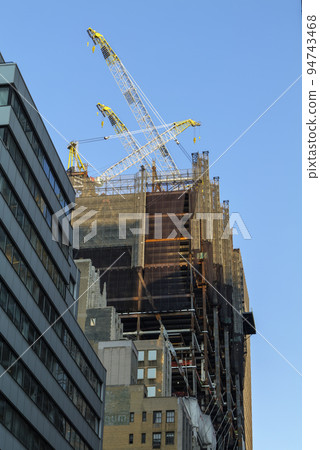 High-rise construction tower crane against the backdrop of a beautiful blue sky. City construction. 94743468