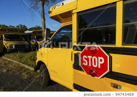 Yellow school bus against blue sky. Stop sign on a side. School bus parking. Back to school concept. Yellow school bus against blue sky. Stop sign on a side. School bus parking. Back to school concept. 94743489