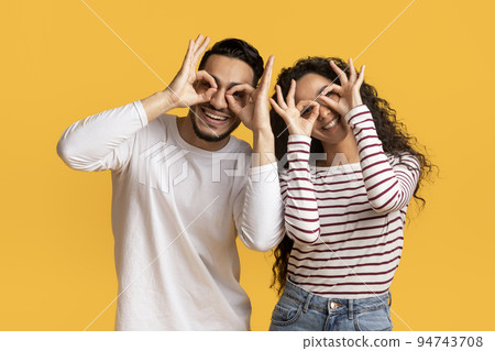 Cheerful middle eastern couple making funny glasses with fingers Cheerful middle eastern couple making funny glasses with fingers 94743708