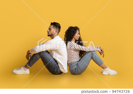 Young Arab Man And Woman Sitting Back To Back Over Yellow Background 94743726