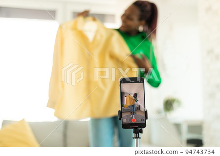 Modern fashion blogger making video review with new clothes after successful shopping, recording video on smartphone 94743734