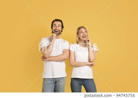 Smiling inspired pensive handsome young caucasian woman and man in white t-shirts, thinks, looks up at empty space Smiling inspired pensive handsome young caucasian woman and man in white t-shirts, thinks, looks up at empty space 94743758