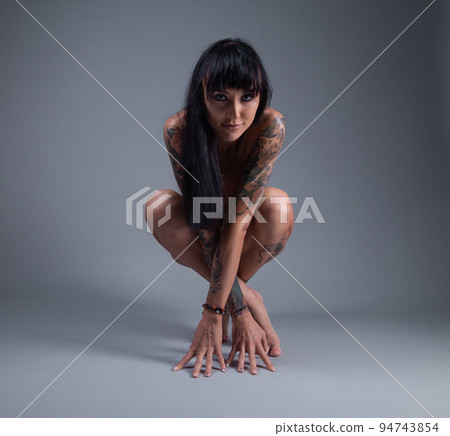 Photo of the nude girl with tattoo sitting on the floor 94743854
