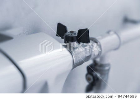 turns the heating on and off. Radiator Heating On The Background of the Wall 94744689