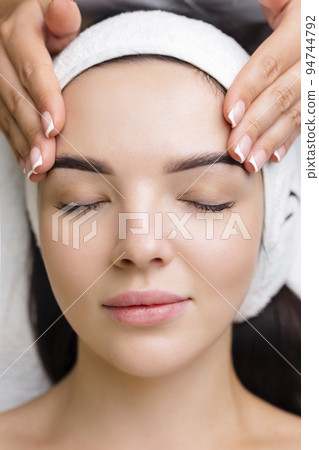 Professional anti-aging facial massage. Action. Relaxing facial treatment at Spa. Relaxing and rejuvenating facial massage for women 94744792