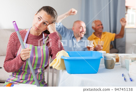 Woman sitting while cleaning house, husband and father watching tv 94745138