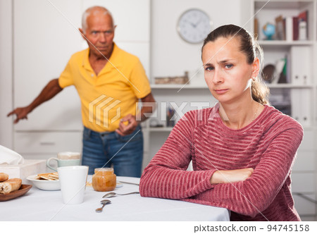 Upset young woman sitting after quarrel with father at home Upset young woman sitting after quarrel with father at home 94745158